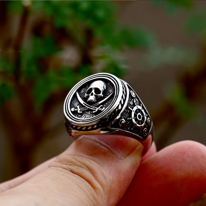 Detailed view of The Captain's Oath ring being held, showing its bold design with a skull and crossed swords centerpiece.