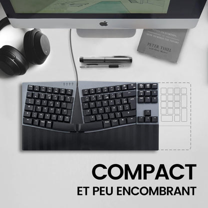 Ergonomic keyboard on a minimalist desk next to a Mac, highlighting its compact design.