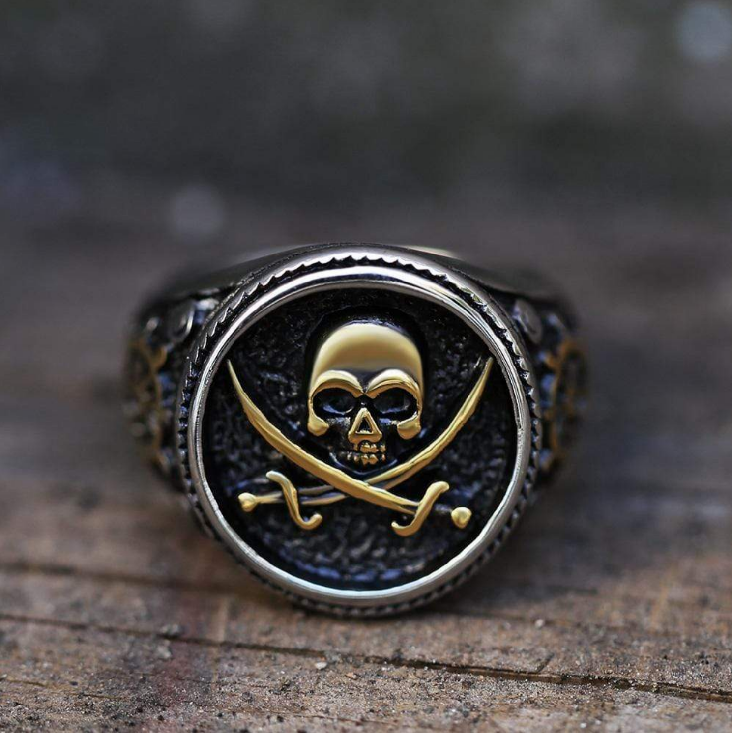 Closeup of a pirate ring featuring a gold skull and crossbones design against a dark textured background.