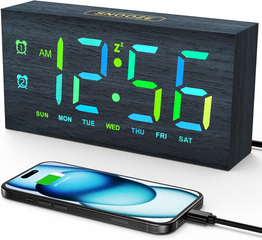 Wooden LED alarm clock displaying the time with a smartphone charging through its USB port.