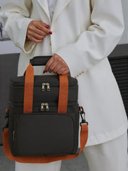 Black insulated lunch tote held by a woman in white blazer, showcasing sleek design.