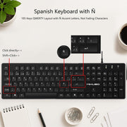 A black wired keyboard with Spanish N key styling, shown on a white desk with text explaining the QWERTY layout with ¡tilde accent letters. The image includes callout boxes and arrows pointing to key areas, plus decorative props like a plant, coffee cup, notebook, pencil, and paper clips.