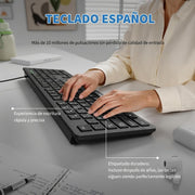 A black wireless computer keyboard shown on a desk with a person typing on it. The image includes Spanish marketing text highlighting the Spanish layout and durable key labeling.