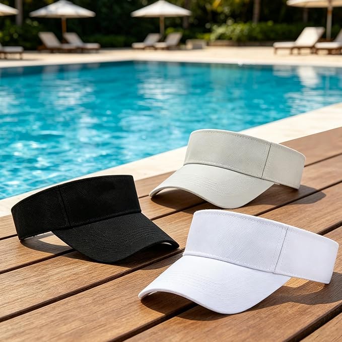 Black, white and beige sun visor hats displayed beside a swimming pool